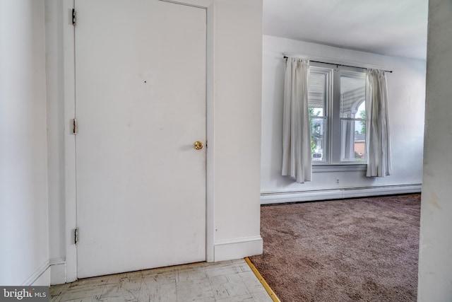 foyer entrance with a baseboard heating unit and light colored carpet