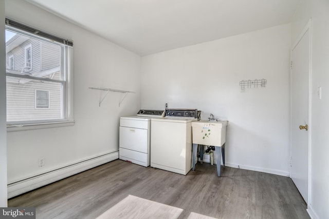 laundry area featuring light hardwood / wood-style floors, sink, baseboard heating, and washing machine and clothes dryer