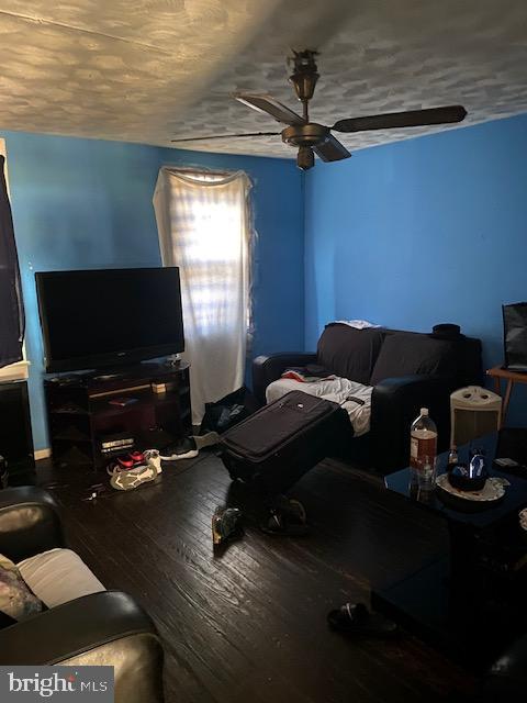 living room with ceiling fan, wood-type flooring, and a textured ceiling