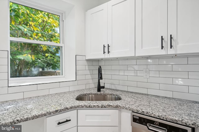 kitchen with sink, a wealth of natural light, stainless steel dishwasher, and white cabinets