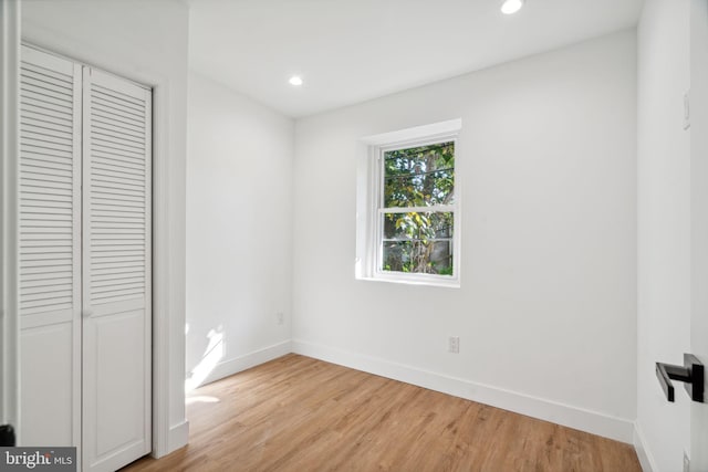 unfurnished bedroom with light hardwood / wood-style flooring and a closet