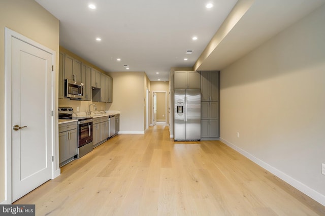 kitchen with gray cabinetry, sink, light hardwood / wood-style flooring, and appliances with stainless steel finishes