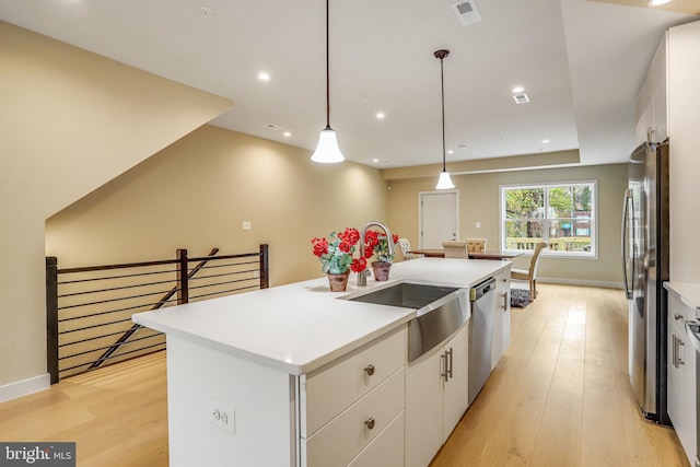 kitchen featuring pendant lighting, a kitchen island with sink, white cabinets, sink, and stainless steel appliances