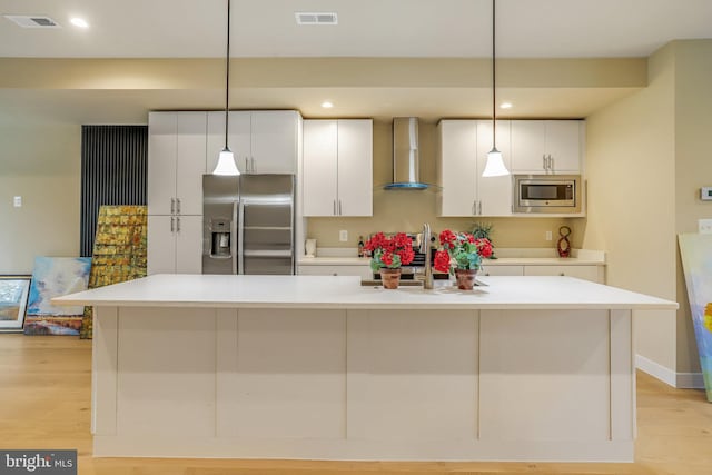 kitchen with a spacious island, pendant lighting, wall chimney exhaust hood, and stainless steel appliances