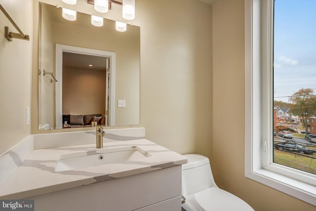 bathroom with vanity, toilet, and a healthy amount of sunlight