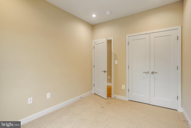 unfurnished bedroom with light carpet and a closet