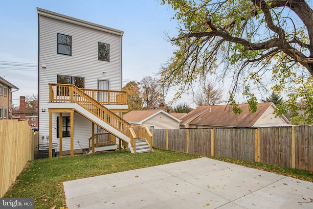 rear view of house featuring a deck, a patio area, and a lawn