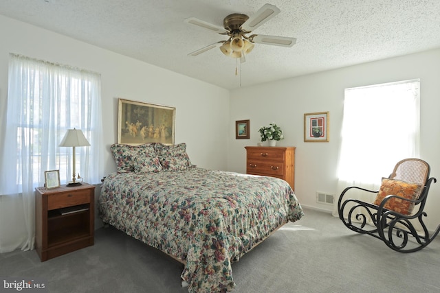 carpeted bedroom featuring ceiling fan and a textured ceiling