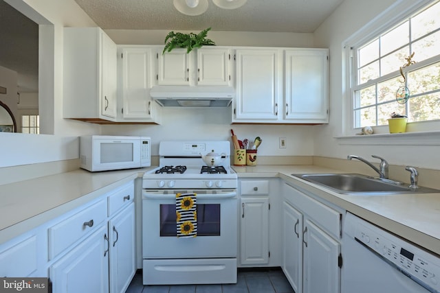 kitchen with a textured ceiling, white cabinetry, sink, and white appliances