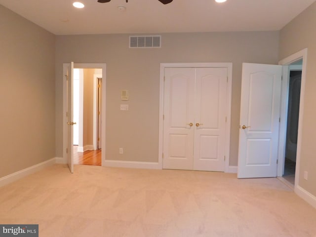 unfurnished bedroom featuring light carpet, a closet, and ceiling fan