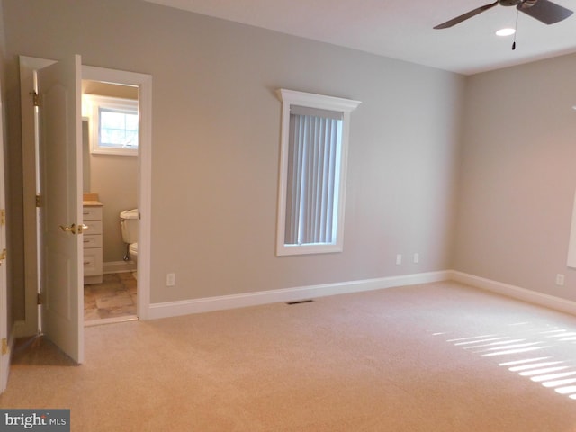 unfurnished bedroom with light carpet, ensuite bath, and ceiling fan