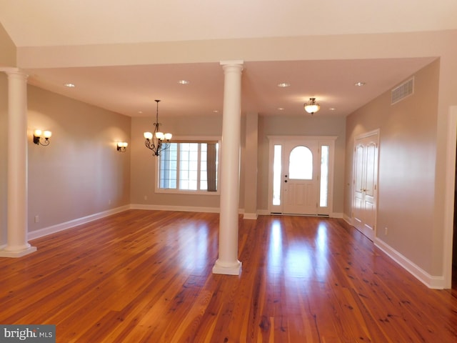 entryway featuring dark wood-type flooring, a chandelier, and decorative columns