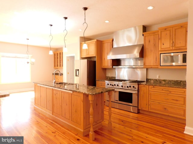 kitchen with appliances with stainless steel finishes, sink, light wood-type flooring, a kitchen breakfast bar, and a center island with sink