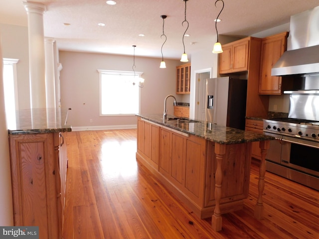 kitchen featuring wall chimney range hood, a spacious island, stainless steel appliances, light hardwood / wood-style floors, and sink