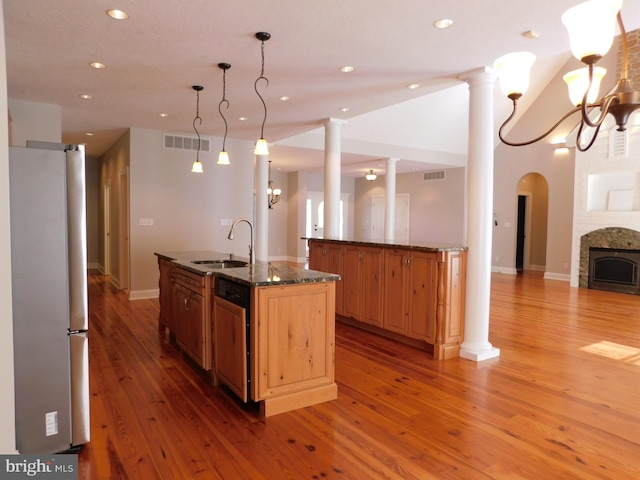 kitchen featuring hardwood / wood-style flooring, stainless steel refrigerator, sink, and an island with sink