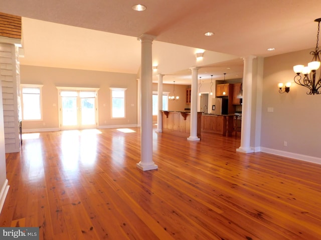 unfurnished living room with sink, hardwood / wood-style flooring, lofted ceiling, and a chandelier