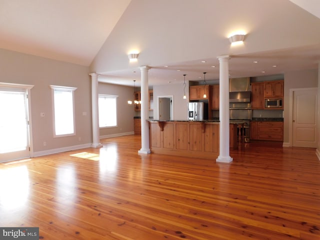 unfurnished living room featuring an inviting chandelier, light hardwood / wood-style flooring, and high vaulted ceiling