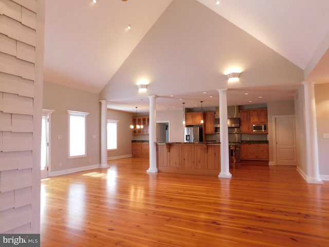 unfurnished living room featuring light hardwood / wood-style flooring, a notable chandelier, and high vaulted ceiling