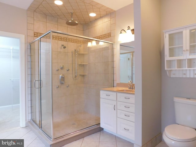 bathroom featuring vanity, a shower with shower door, toilet, and tile patterned floors