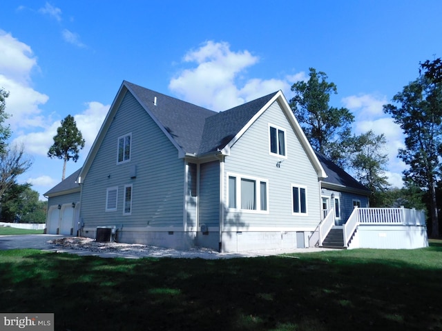 exterior space with a deck, a garage, and a lawn