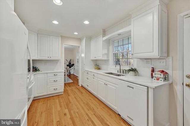 kitchen featuring backsplash, white appliances, sink, light hardwood / wood-style flooring, and white cabinetry