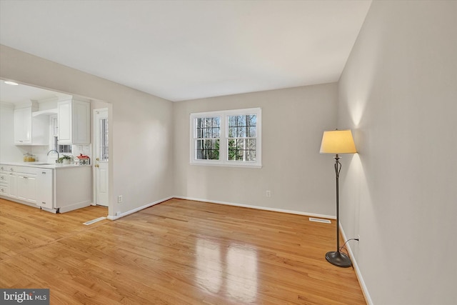 spare room with light hardwood / wood-style floors and sink