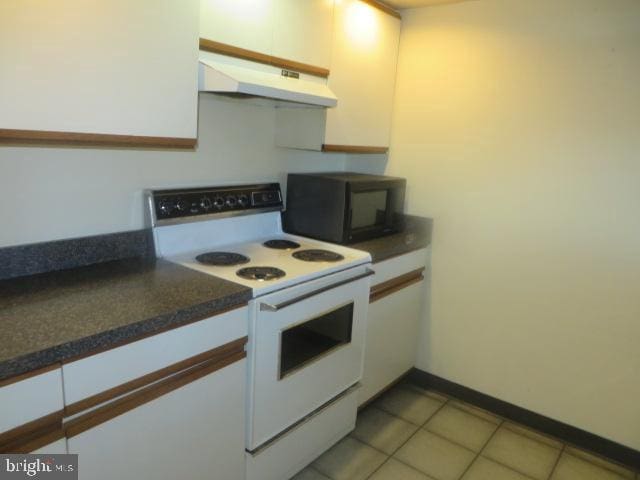 kitchen featuring white cabinets, light tile patterned floors, and white range with electric cooktop