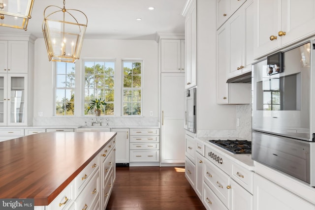 kitchen with a sink, wood counters, white cabinets, and dark wood finished floors