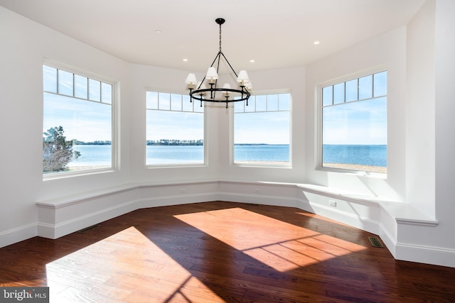 unfurnished dining area with visible vents, plenty of natural light, wood finished floors, and a water view