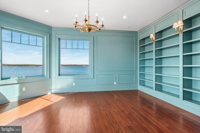 unfurnished dining area featuring dark wood-type flooring, built in features, recessed lighting, an inviting chandelier, and a decorative wall