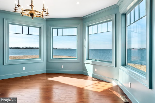 unfurnished dining area with visible vents, a healthy amount of sunlight, wood finished floors, and crown molding