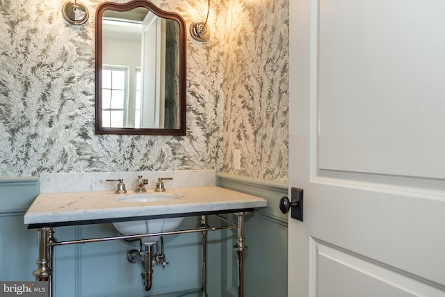 bathroom with wallpapered walls and a sink