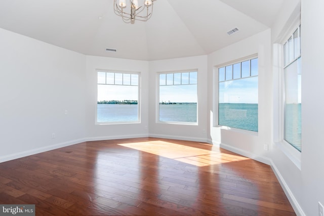 empty room with vaulted ceiling, visible vents, baseboards, and wood finished floors