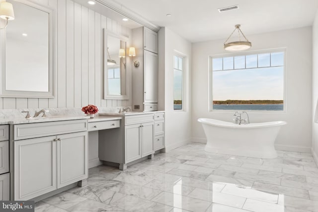 bathroom featuring visible vents, baseboards, a soaking tub, marble finish floor, and vanity