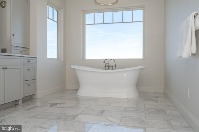 bathroom with a freestanding tub, baseboards, and marble finish floor