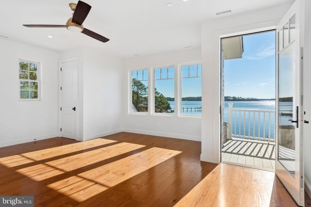 interior space with visible vents, baseboards, wood finished floors, and a water view