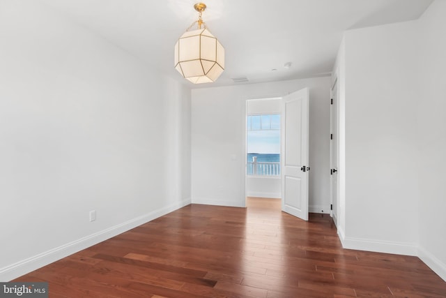 empty room featuring visible vents, wood finished floors, and baseboards