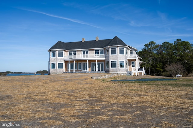 back of house with a balcony and a chimney