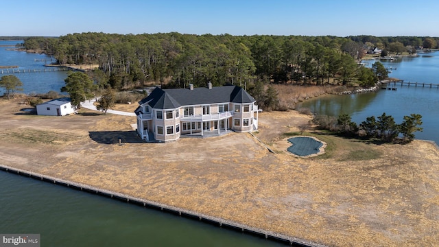 drone / aerial view with a wooded view and a water view