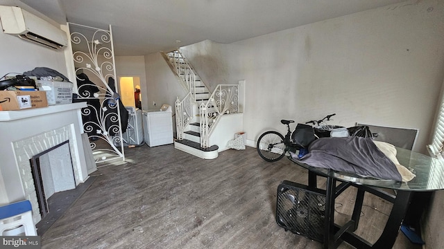 interior space with an AC wall unit, a brick fireplace, dark hardwood / wood-style floors, and washer / clothes dryer