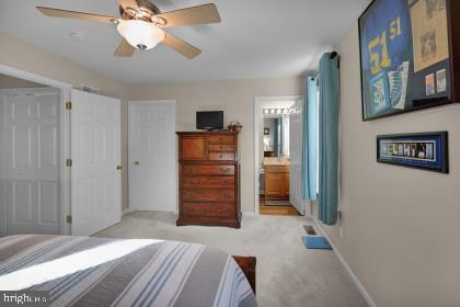 carpeted bedroom with ceiling fan and ensuite bath