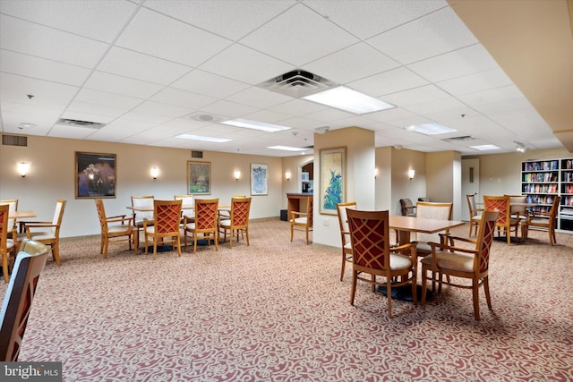 dining space featuring light colored carpet and a paneled ceiling