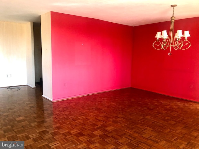 empty room with dark parquet floors and an inviting chandelier