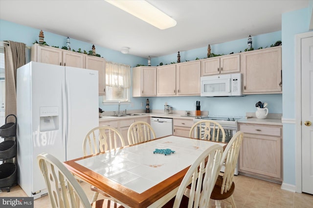 kitchen with light tile patterned floors, white appliances, light brown cabinetry, and sink