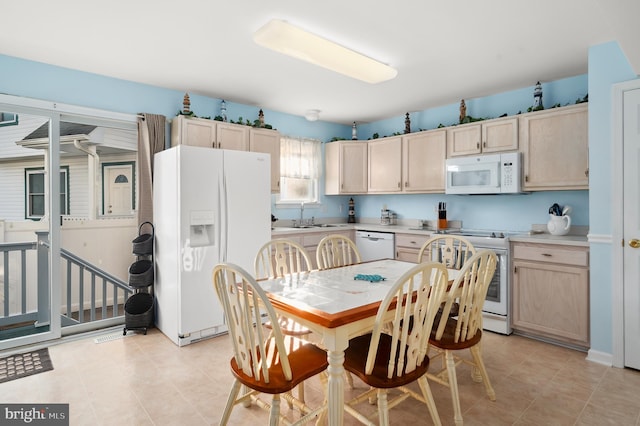 kitchen with light brown cabinets, white appliances, and sink