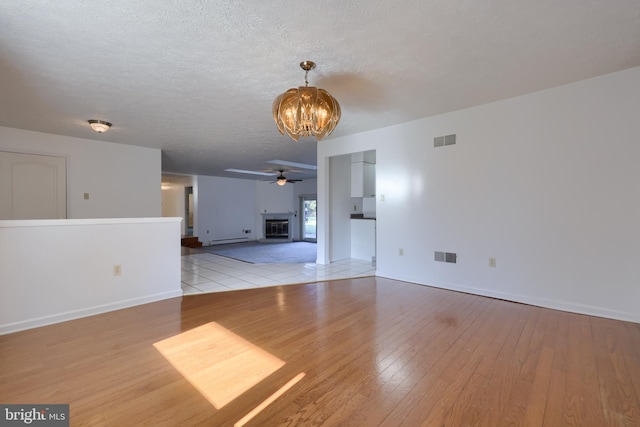 unfurnished living room featuring light wood finished floors, visible vents, and ceiling fan with notable chandelier