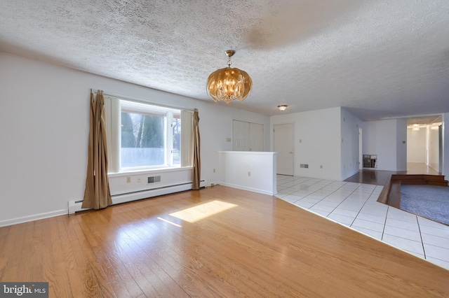 unfurnished living room with an inviting chandelier, a textured ceiling, baseboard heating, and wood finished floors
