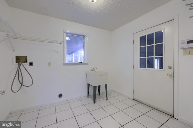 laundry room featuring electric dryer hookup, light tile patterned flooring, hookup for a washing machine, and a textured ceiling