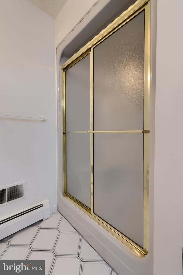 bathroom with a baseboard heating unit, tile patterned floors, a shower with shower door, and visible vents