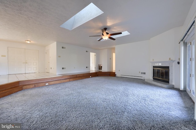 unfurnished living room with a skylight, a baseboard heating unit, carpet, a ceiling fan, and a glass covered fireplace